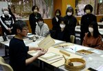 秦さん（手前左）に教わり昭和初期の刊行物などを修復する参加者＝１２日、鳥取市の県立図書館