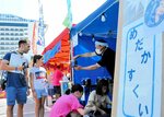 夏祭りのメダカすくいに興味津々の外国人乗船客の親子＝２１日、境港市の境夢みなとターミナル