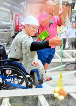 県主催のモニターツアーで湯村温泉街を散策する木村さん。湯つぼからゆがいた卵を引き上げると笑みがこぼれた＝５日、新温泉町湯