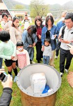 タイムカプセルの中身を興味深そうにのぞき込む卒業生＝８日、香美町香住区上岡の奥佐津小