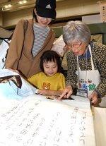 出展者（右端）の説明を受けながら布絵本の展示を楽しむ親子連れ＝１９日、米子コンベンションセンター