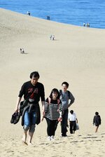 真夏のような日差しを受けながら砂の上を歩く観光客＝２日午後１時ごろ、鳥取市湯山の鳥取砂丘