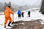 集めた雪をならして滑走箇所を確保する作業に追われる従業員ら＝２２日、若桜町〓米のわかさ氷ノ山スキー場