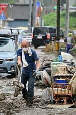 　大雨から一夜明け、道路の泥を片付ける住民＝９日午前、福島県いわき市