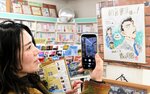 店内に掲示されている今年の色紙をスマートフォンで撮影する観光客＝１４日、北栄町由良宿の朝倉書店