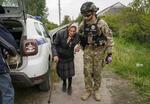 　ウクライナ東部ハリコフ州で、警察官（右）の助けを受けてハリコフ市へ避難する女性＝１３日（ロイター＝共同）