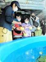バックヤードツアーで魚の餌やりを体験する家族＝兵庫県豊岡市の城崎マリンワールド