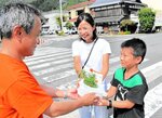 上川町長（左）から花を受け取る地域住民＝２３日、若桜町若桜の若桜駅前