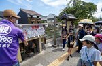 観光ガイド（左）の解説で加茂川沿いの地蔵を巡る参加者ら＝３０日、米子市内町