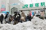 　雪が残るＪＲ新宿駅前を歩く人たち＝６日午前