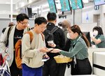 航空会社のスタッフから記念のどら焼きを受け取る利用者＝２５日、鳥取県境港市の米子鬼太郎空港