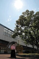 強い日差しが照りつける中、日傘を差して歩く市民＝１４日午後２時２０分ごろ、ＪＲ鳥取駅前