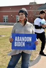 　２７日、米ミシガン州ディアボーンの予備選投票所前で「バイデンを見捨てよう」と書かれたプラカードを持つサムラ・ルクマンさん（共同）