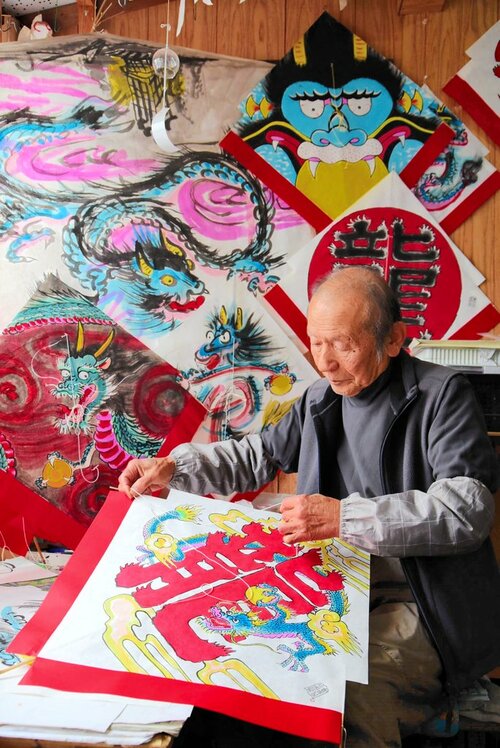 「昇り龍で、景気も回復して」と願いを込めて凧を作る松嶋さん＝２０日、倉吉市瀬崎町