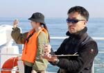 　大阪湾でスナメリの調査をする神戸大大学院海事科学研究科の岩田高志助教（右）ら＝２０２３年１１月
