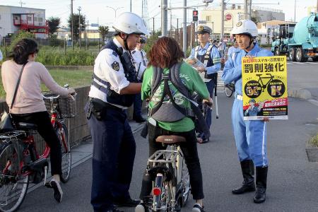 　昨年１０月、自転車走行中の携帯電話使用などに罰則を新設した改正道交法の施行を前に、新たなルールを周知する埼玉県警の警察官ら＝埼玉県草加市