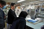機械で刺しゅうが施される様子を見学する参加者ら＝１５日、若桜町浅井の安泰ニット若桜工場