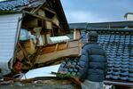 　地震で倒壊した自宅兼倉庫を見つめる男性。「建て直そうとは思わない。もうここには住めないかな」＝６日午前８時１９分、石川県能登町