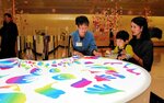 自分の顔が映るテーブルで鑑賞を楽しむ親子。専門家は「子どもとの関わり方を工夫すれば、鑑賞はぐんと楽になる」と話す＝鳥取市の鳥取県立博物館