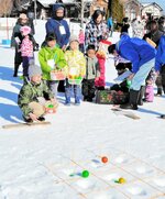 雪上に掘った穴にボールを入れる玉入れに挑む子どもたち＝１９日、新温泉町丹土の県立但馬牧場公園