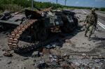 　ウクライナ南部ザポロジエ州ロボティネ近くで破壊された戦車の横を歩くウクライナ兵＝２５日（ロイター＝共同）