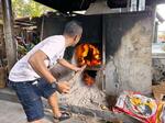 　サウナのかまどの火にまきをくべる男性＝２０２４年２月、バンコク（共同）