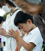 　原爆慰霊碑の前で手を合わせる子どもら＝６日午前５時４３分、広島市の平和記念公園