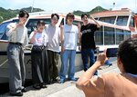 紹介する観光スポットで写真を撮る学生ら＝４日、岩美町大谷の山陰松島遊覧