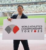 　東京で開催される陸上世界選手権の大会ロゴを手にする中川亮さん＝１３日、東京・国立競技場