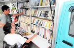 移動図書館車の書架から本を選ぶ「まつぼっくり事業所」の利用者＝１８日、境港市岬町