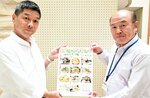 「味めぐりスタンプラリー」のチラシを掲げるスタッフ