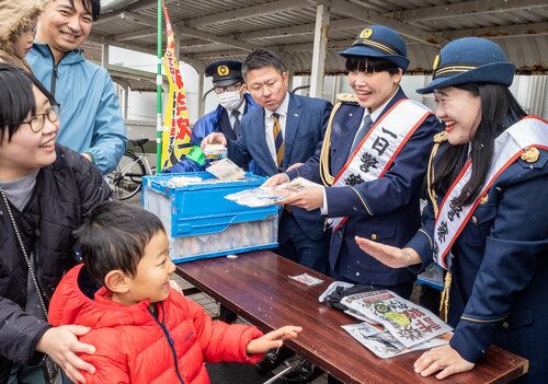 町民に啓発グッズを手渡すガンバレルーヤの（右から）よしこさん、まひるさん＝１７日、大山町所子