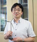 　洋上風力発電の風車の模型を手にする神戸大大学院の大澤輝夫教授＝６月、神戸市東灘区