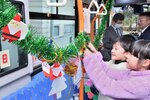 自作したクリスマス装飾を路線バスの車内に飾り付ける児童ら＝１２日、鳥取市徳尾の世紀小