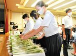 白いバラを献花する参列者たち＝２８日、大山町末長の大山公民館