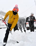 雪が舞う中、黙々と除雪作業をする大学生＝２４日、鳥取市湖山町南５丁目