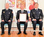 野田消防長（左）から感謝状を受け取った仲山さん（中央）＝８日、新温泉町今岡の美方広域消防本部