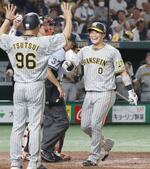 　７回、満塁本塁打を放ち、コーチに迎えられる阪神・木浪（右）＝東京ドーム