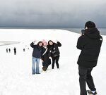 雪化粧した砂丘を背景に記念撮影する観光客＝２１日、鳥取市福部町湯山の鳥取砂丘