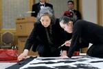　輪島塗の墨つぼなどを使って揮毫する金沢翔子さん（右）。見守るのは母泰子さん＝２０１５年１１月、東京都内