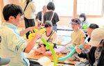 ＧＷのイベントで高校生（左）とバルーンアートで交流する子どもたち