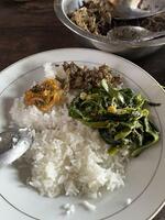 　ミャンマー北西部チン州テイザーンの宿舎で取材班に提供された食事。菜の花の煮物と干し魚などが米飯に載っている＝３月１２日撮影（共同）