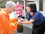 事業所にオレンジ色の花を配布する参加者（左）