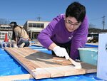 はけで丁寧に防腐剤を塗る参加者＝１０日、鳥取市鹿野町鹿野の鳥の劇場