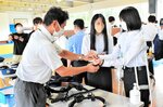 警察官（左）と話しながら手錠を手に取る参加者＝９日、鳥取市伏野の鳥取県警察学校