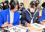 生徒（右）に教わりながら筆で「愛」の文字を書く留学生＝２３日、香美町村岡区の村岡中