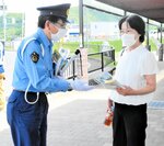 来店客に啓発グッズを手渡す署員＝２０日、新温泉町栃谷の道の駅山陰海岸ジオパーク浜坂の郷