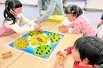 サイコロを振って果物を集めるゲームに挑戦する子どもたち