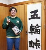 　焼酎「五輪峠」のビンを持つ斎藤柊斗さん＝２０２４年４月、新潟県三条市