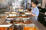 　にぎわうミャンマー料理店の厨房で盛り付けをする店員＝２０２４年５月、タイ・バンコク（共同）